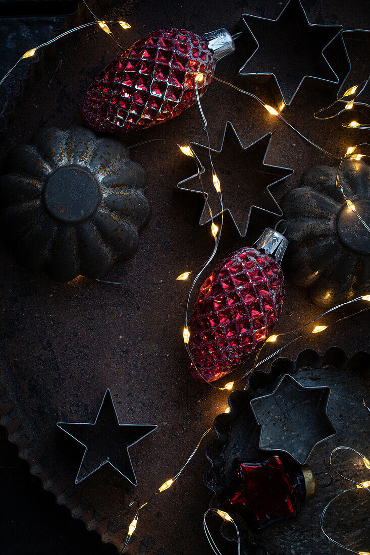 Alte Plätzchenform auf Blech mit altem Weihnachtsbaumschmuck und Lichterkette