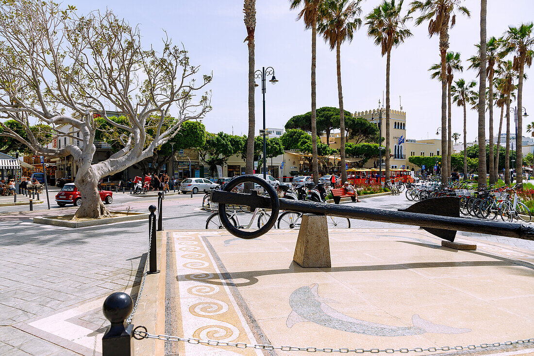 Hafenpromenade mit Delphinmosaik, Mietfahrrädern, Touristenzug und Rathaus in Kos-Stadt auf der Insel Kos in Griechenland