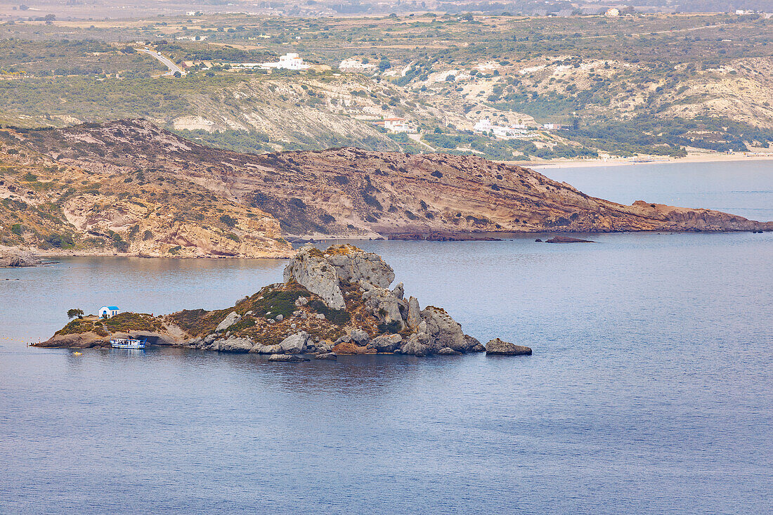  Excursion boat anchored near the island of Kastri with the chapel of Agios Nikolaos in the bay of Kefalos on the island of Kos in Greece 