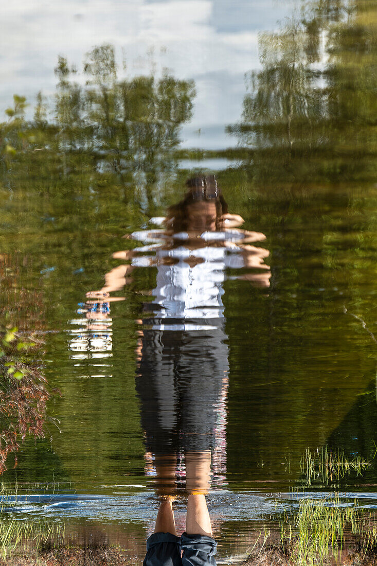 Anonymous woman walking a flooded boardwalk in the Mastbos, a small forest located on the edge of Breda, the Netherlands.