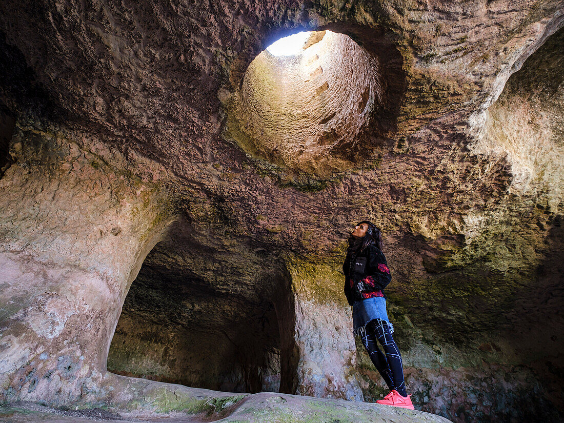 tourist observing a skylight, necropolis, Cala Morell, Ciutadella, Menorca, Balearic Islands, Spain