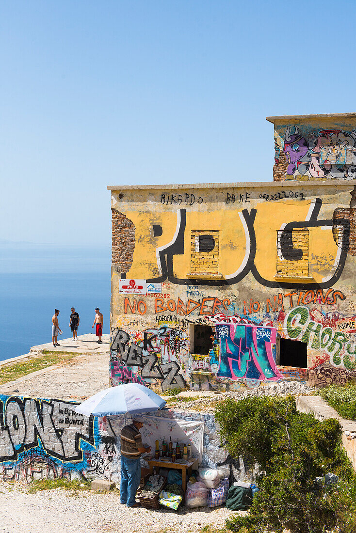 Local produce dealer (honey, olive oil, medicinal herbs) and construction abandoned and spray painted at the edge of the SH8 road through the Llogara National Park, a national park centered on the Ceraunian Mountains along the Albanian Riviera in Southwestern Albania, Southeastern Europe