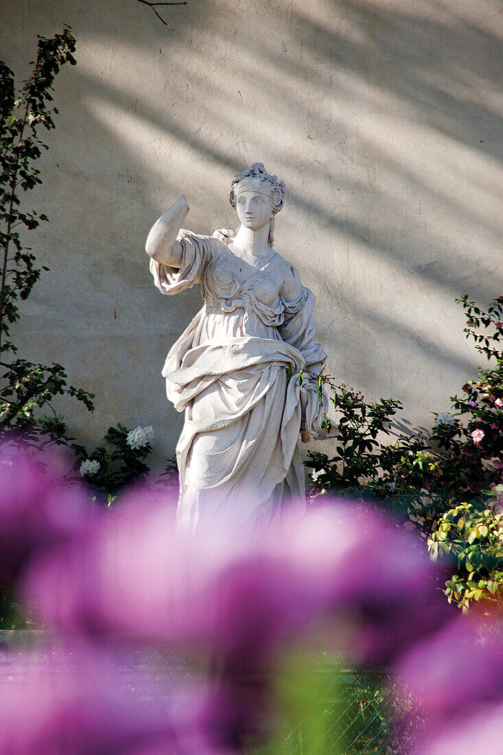 Statue vor rosa Blumen