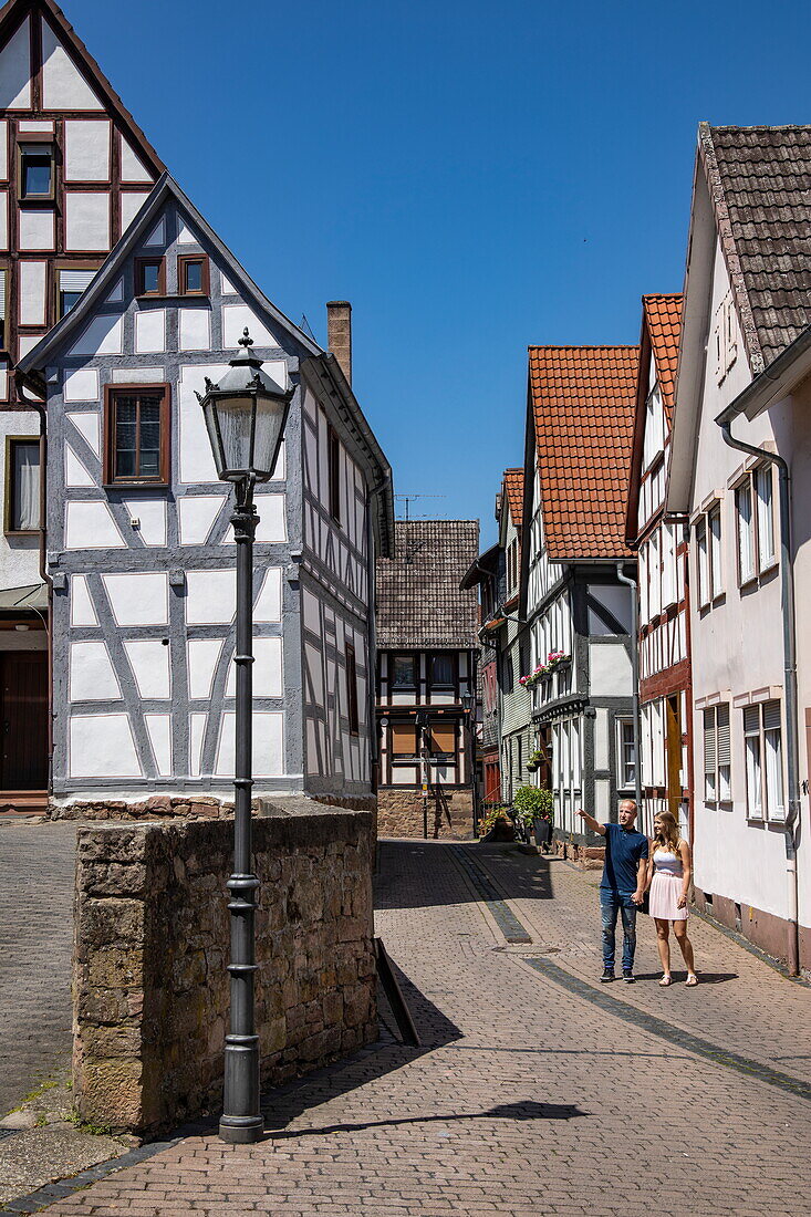 Paar schlendert entlang einer Kopfsteinpflasterstraße mit Fachwerkhäusern in der Altstadt, Steinau an der Straße, Spessart-Mainland, Hessen, Deutschland