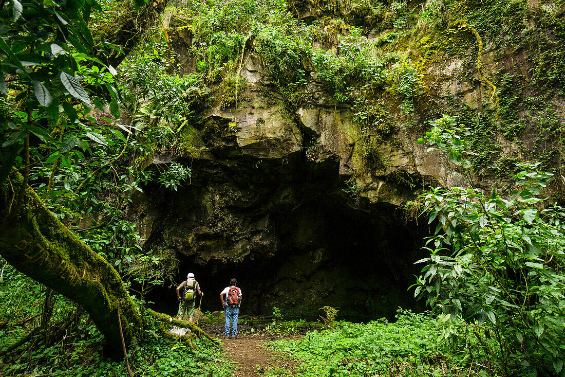 Hikers in front of a Mayan ritual cave, cloud forest on the slopes of Tolimán volcano, Lake Atitlán, Guatemala, Central America