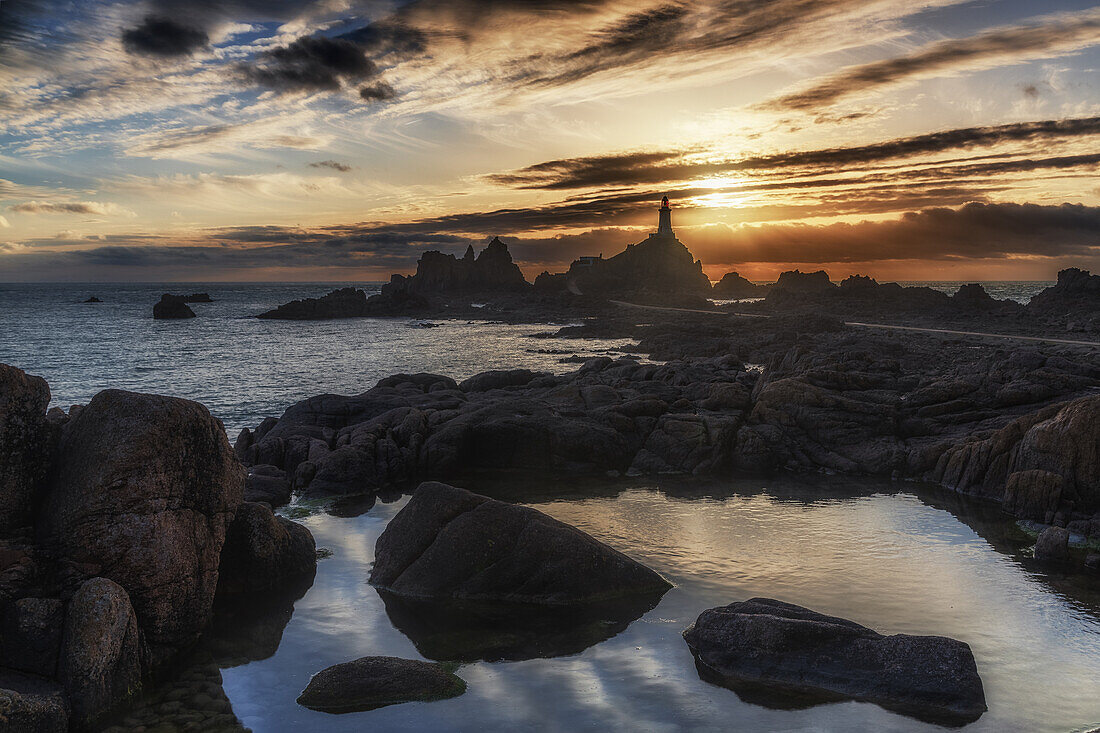  Le Corbiere lighthouse at sunset during low tide. Reflection in the foreground. 