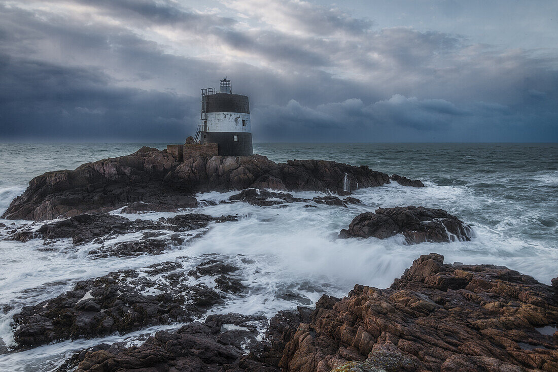  Tour de Vinde lighthouse at the Noirmont lookout point in wind and waves. Rocky coast. 