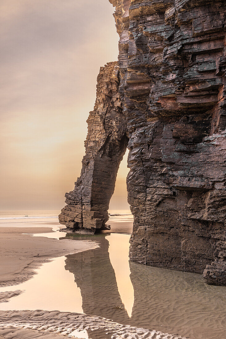  Rock arch on the beach of Playa de las Catedralas. Tide pool in the foreground. Golden hour. 