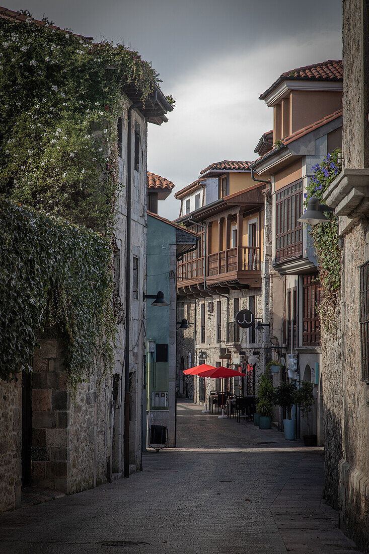  Deserted old town street in Llanes with a red parasol. 