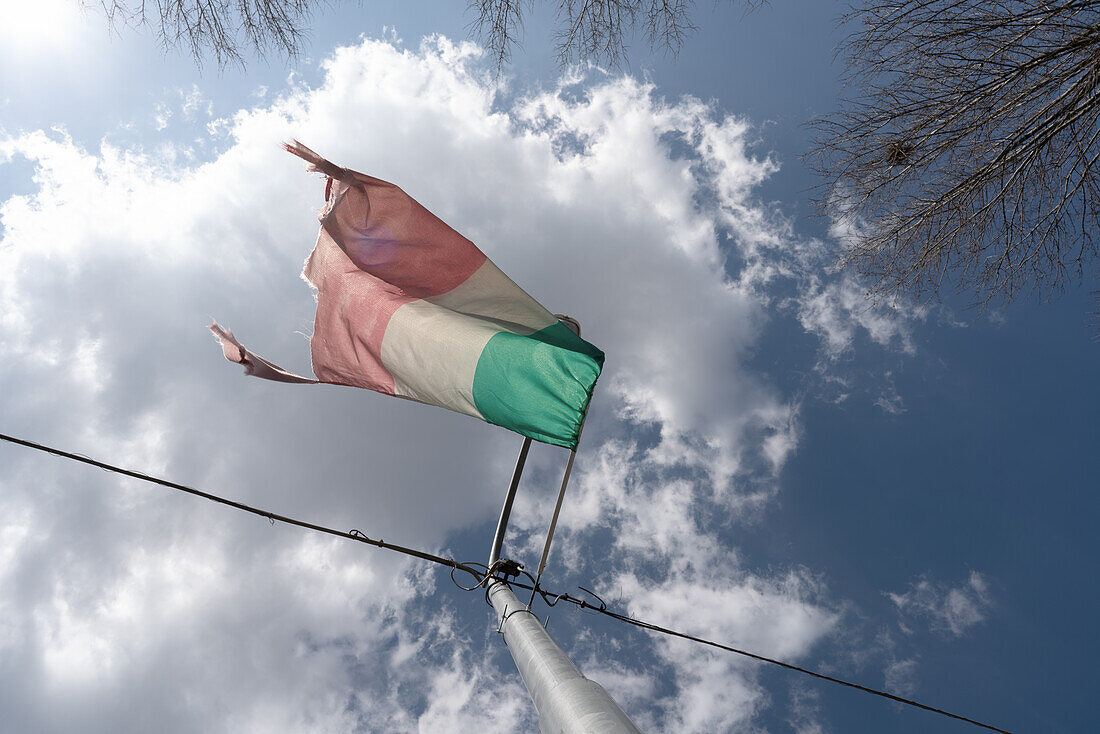 old and ruined italian flag  against a cloudy sky