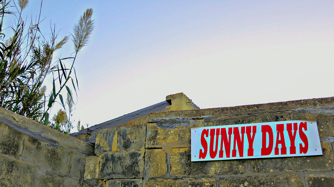 Sunny Days Schild auf alter Steinmauer im Sonnenuntergang, Insel Gozo, Malta