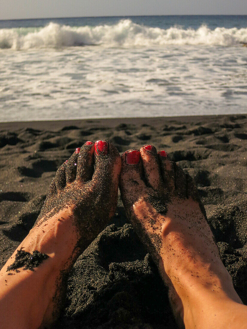  Woman&#39;s feet on the black lava beach with red nail polish on Gozo/Malta November 2015 