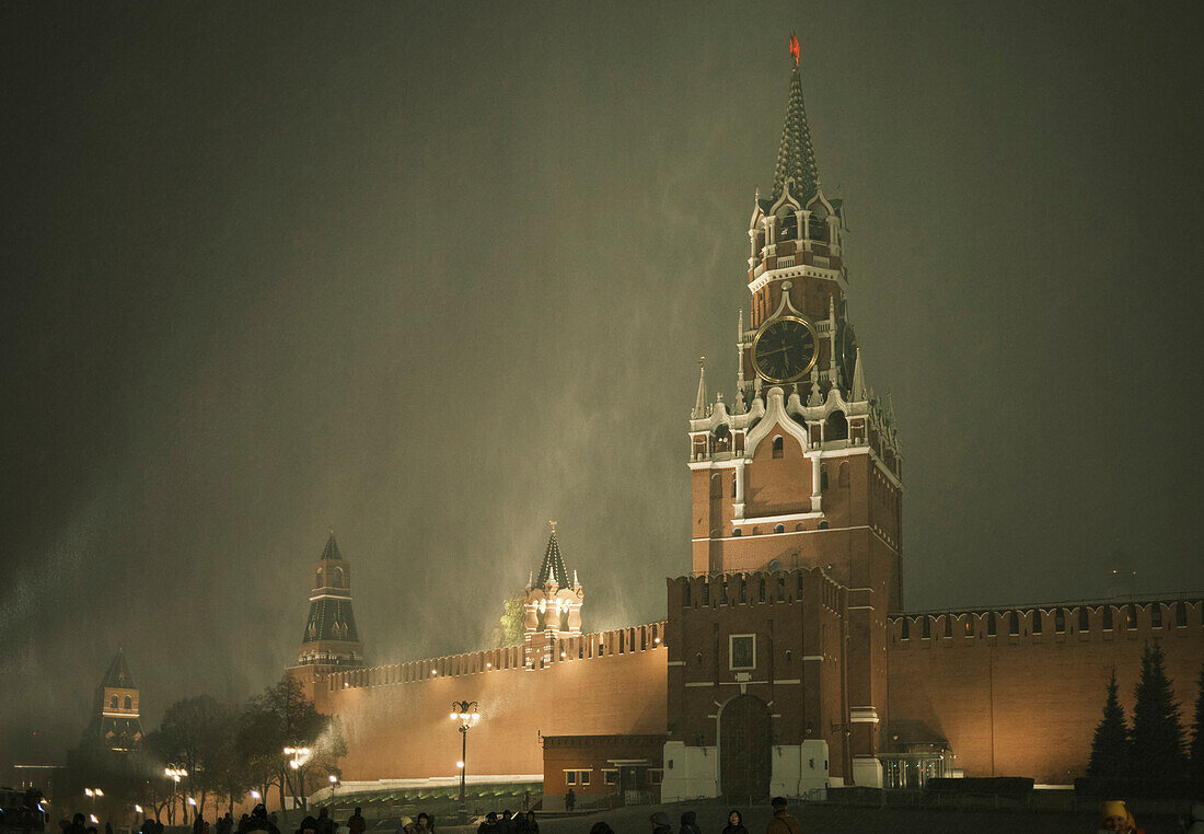  Blick auf den Spasskaja-Turm und die Kremlmauer während eines plötzlichen Schneesturms in der Nacht. Moskau, Russland. 