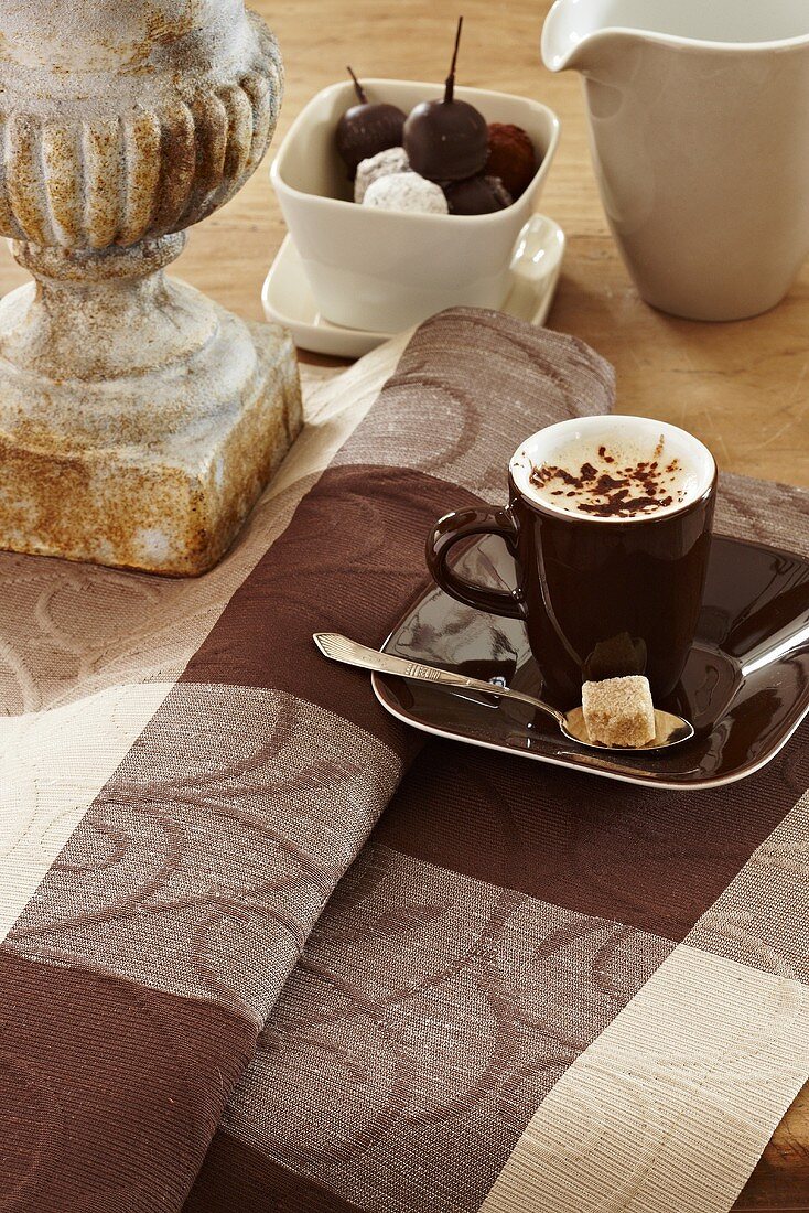 Eine Tasse Cappuccino auf braun karierter Tischdecke
