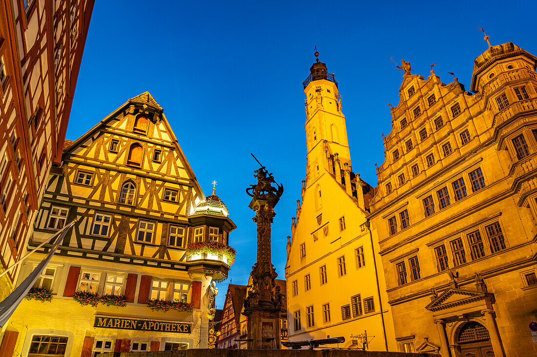  Georgsbrunnen, Marien-Apotheke, town hall and town hall tower in Rothenburg ob der Tauber at dusk, Bavaria, Germany  