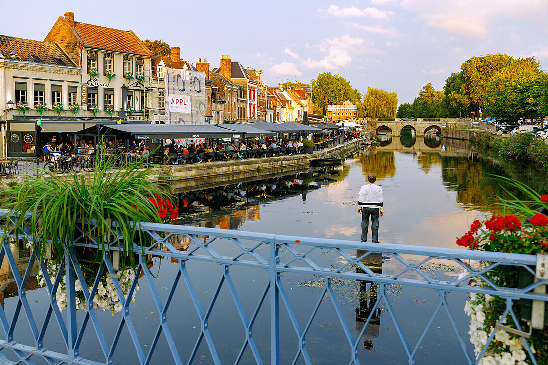  Quai Bélu (Belu) on the Somme with wooden sculpture &quot;L&#39;homme sur sa bouée&quot; (1993) by Stephan Balkenhol in the Saint-Leu district and view of the Pont du Cange bridge in Amiens in the Somme department in the Hauts-de-France region of France 