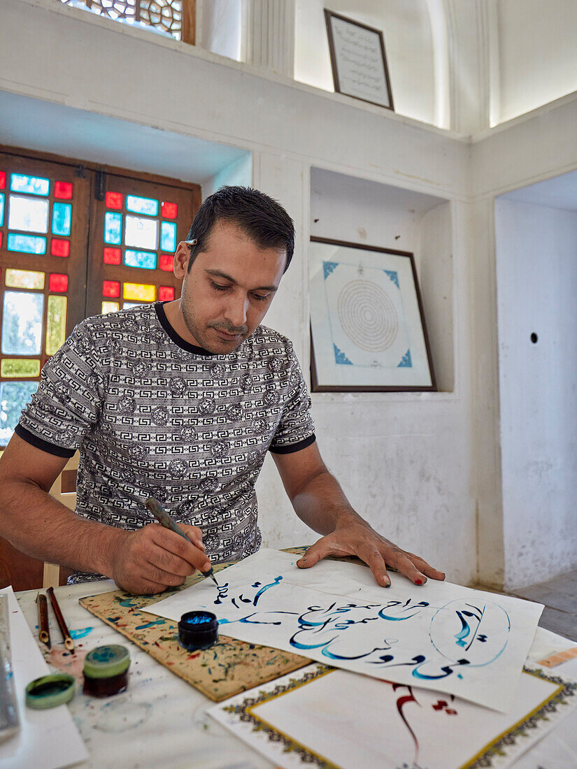 Calligrapher at work in the Fin Garden (Bagh-e Fin), oldest (1590) existing Persian Garden in Iran and UNESCO World Heritage Site. Kashan, Iran.