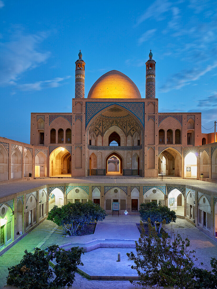 Blick auf die Agha-Bozorg-Moschee aus dem 18. Jahrhundert und Innenhof, beleuchtet in der Abenddämmerung. Kashan, Iran.