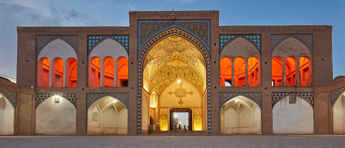 Panoramic view of the main entrance gate of the 18th century Agha Bozorg Mosque illuminated at dusk. Kashan, Iran.