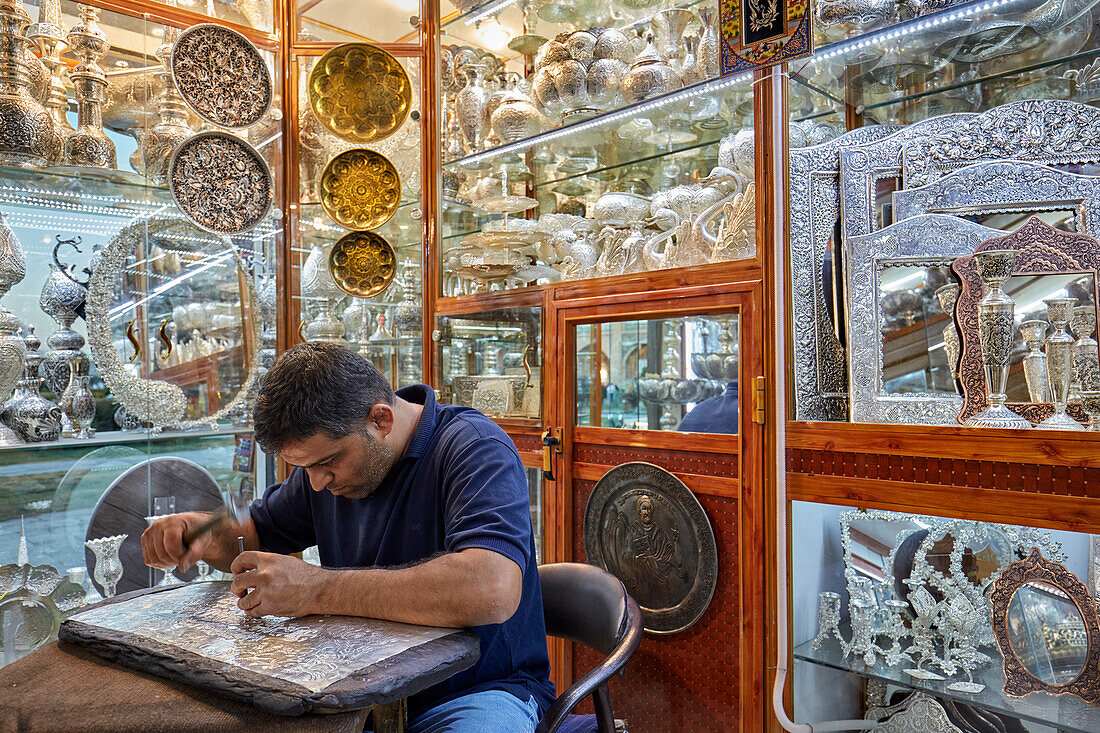 Qalamzani, or Ghalamzani (traditional Iranian metal engraving art) artist works in a handicraft store. Isfahan, Iran.