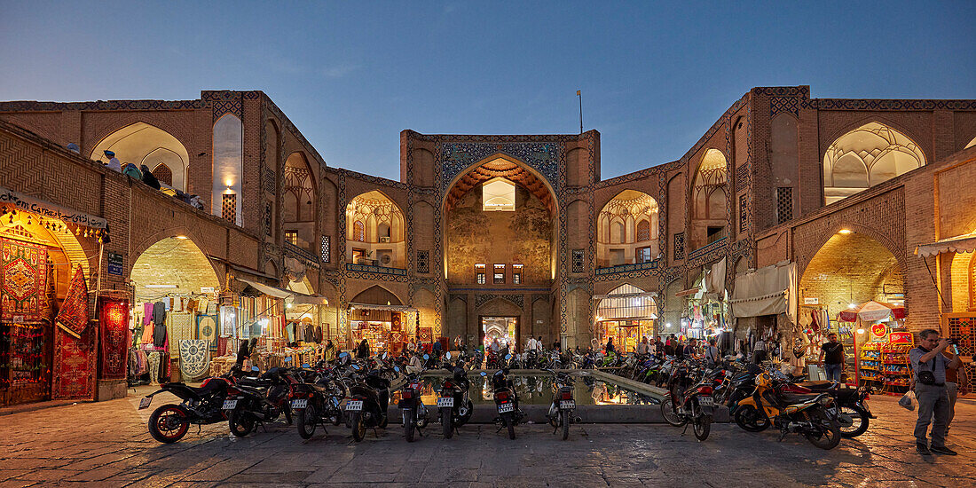 Motorbikes parked at the illuminated Qeysarie Gate, the main gateway to the Grand Bazaar of Isfahan in Naqsh-e Jahan Square. Isfahan, Iran.