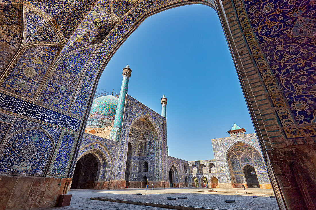 Courtyard view of the Shah Mosque (Masjed-e Shah) through an arch with elaborate tiling. Isfahan, Iran.