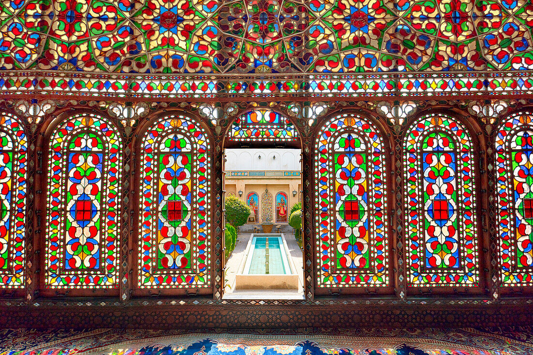 Large ornate stained glass windows in the shahneshin (a dedicated reception room) of the Mollabashi Historical House in Isfahan, Iran.