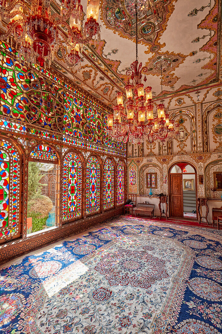  Innenansicht des Shahneshin (ein spezieller Empfangsraum) mit großen farbenfrohen Buntglasfenstern im historischen Mollabashi-Haus in Isfahan, Iran. 