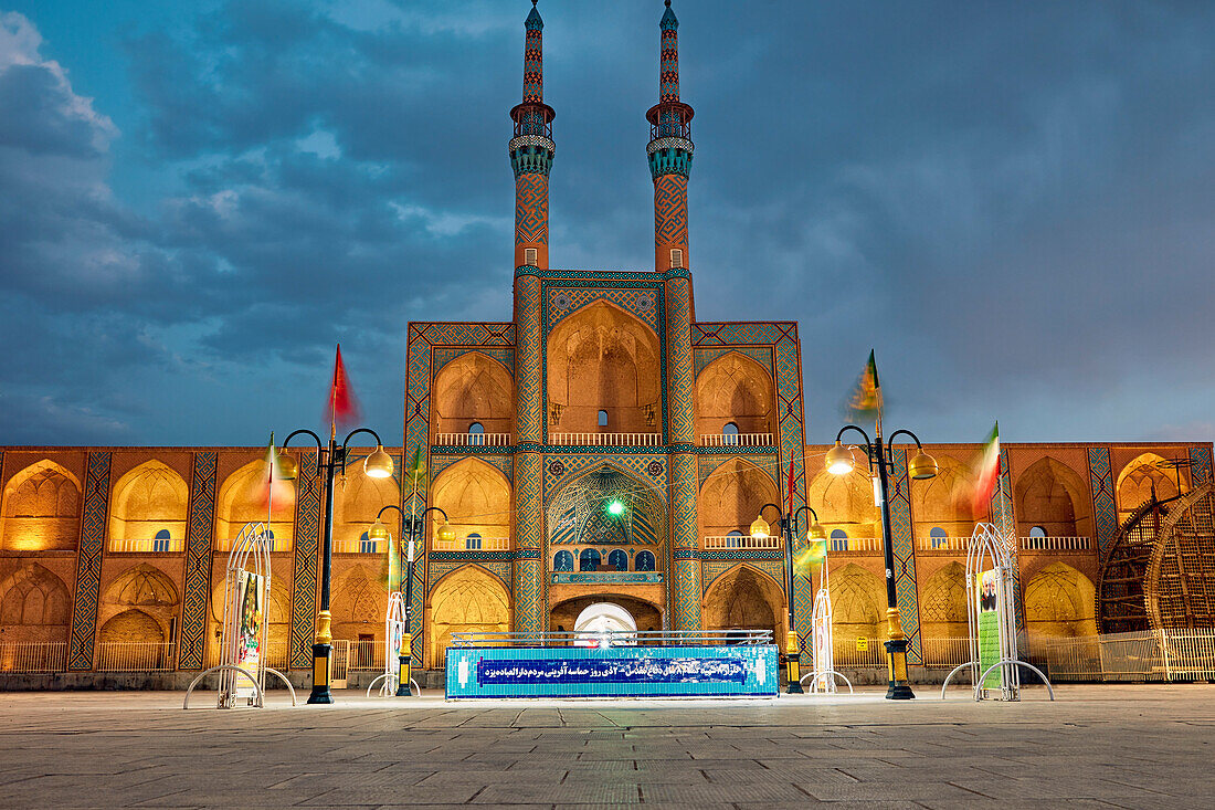 Takyeh (building where Shia Muslims gather to mourn Husayn's death) and minarets of the Amir Chakhmaq Complex illuminated at night. Yazd, Iran.