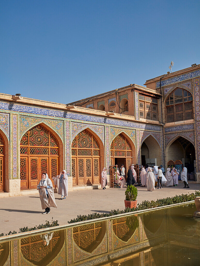 Tourists in the courtyard of the 19th century Nasir al-Mulk Mosque, aka the Pink Mosque. Shiraz, Iran.