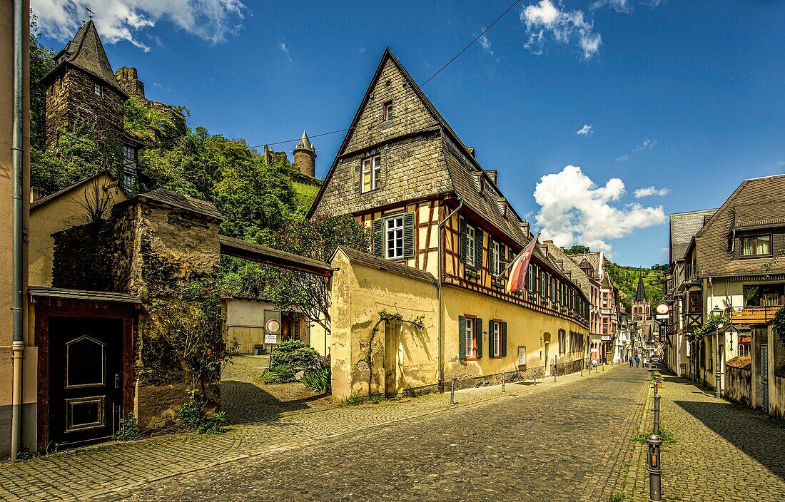  Mainzer Straße in the old town of Bacharach, on the left the town hall, Stahleck Castle and fortress towers, Upper Middle Rhine Valley, Rhineland-Palatinate, Germany 