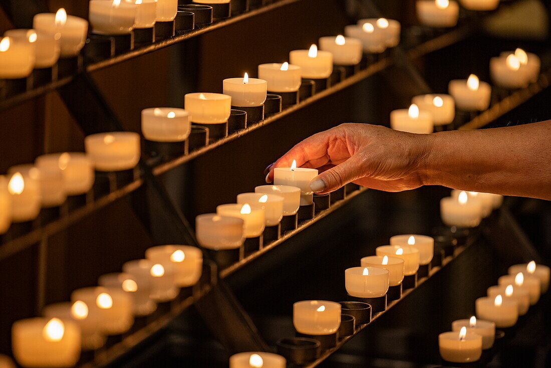  Hand lighting candle in Notre-Dame Cathedral, Luxembourg, Luxembourg, Europe 