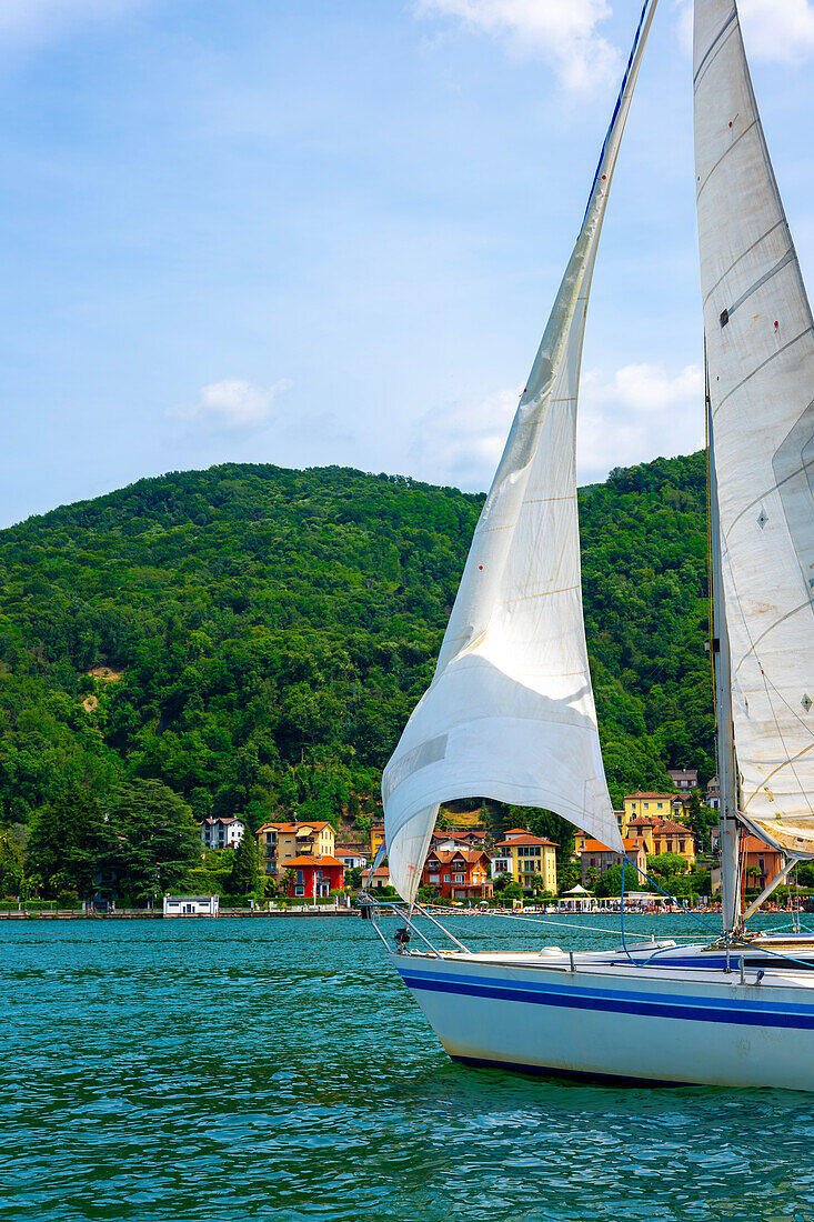  Blick von einem Segelboot auf den Luganersee und Häuser und Bergketten an einem sonnigen Sommertag am Ufer in Lugano, Tessin, Schweiz. 