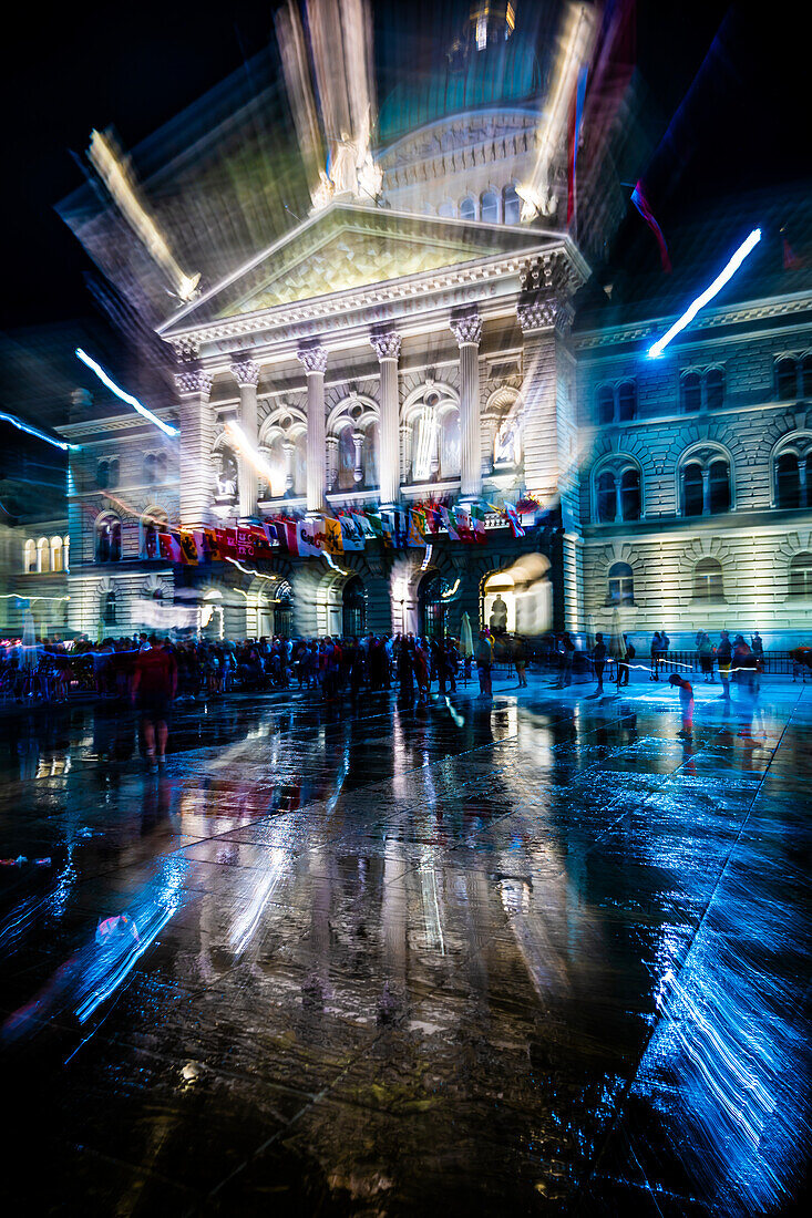 Beleuchtetes Bundeshaus, Parlamentsgebäude, Bundespalast in einer regnerischen Nacht mit Menschenmenge in der Stadt Bern, Kanton Bern, Schweiz.