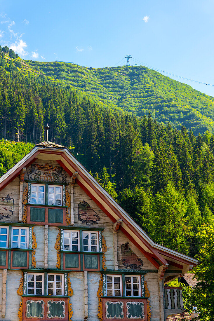 Altstadt mit einem Haus und einem Berg an einem sonnigen Sommertag in Andermatt, Uri, Schweiz.