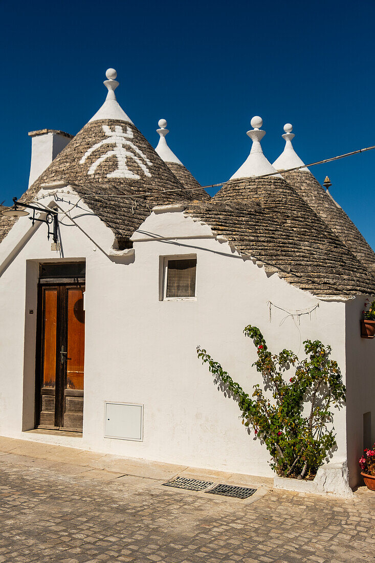  Trulli-Häuser mit Symbolen auf den Dächern in Alberobello, Apulien, Italien. 