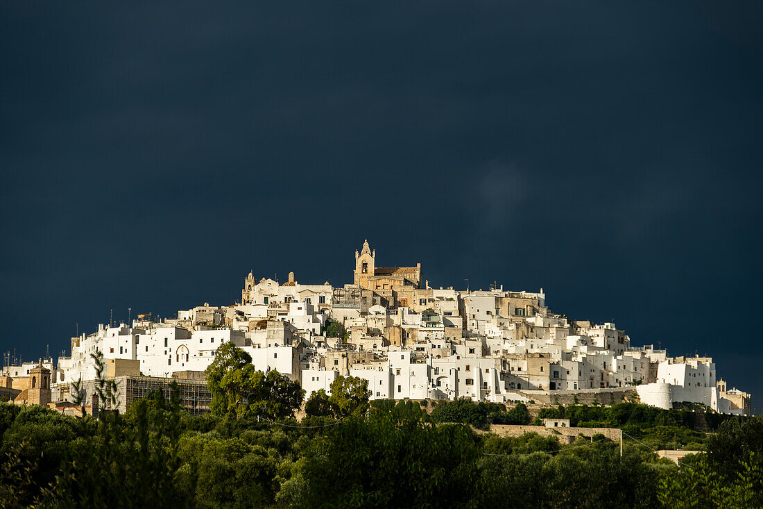 Altstadt von Ostuni mit einem dunkel bewölkten Himmel, Apulien, Italien.