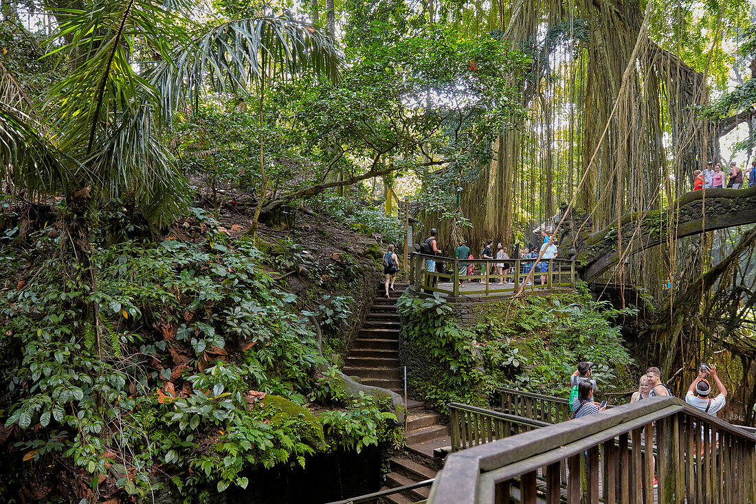  Touristen gehen auf einem Pfad mit Treppen und Lichtbrücken im Sacred Monkey Forest Sanctuary. Ubud, Bali, Indonesien. 