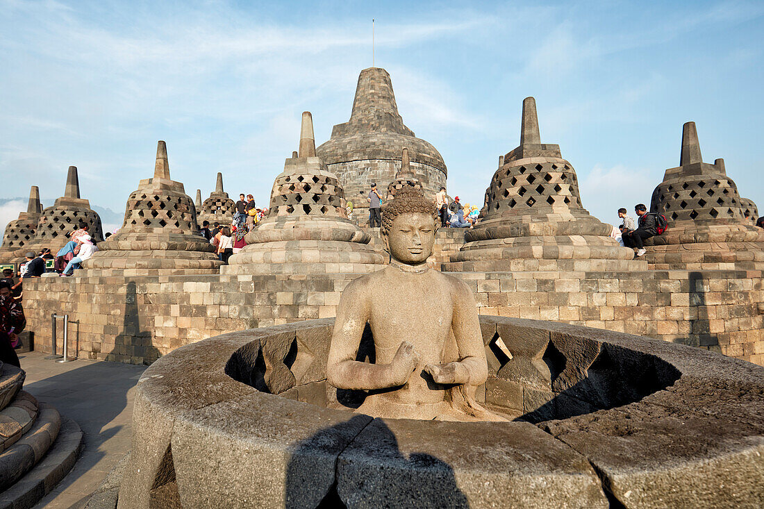 Buddha statue with the hand position of Dharmachakra mudra, representing Turning the Wheel of Dharma. Borobudur Buddhist Temple, Java, Indonesia.