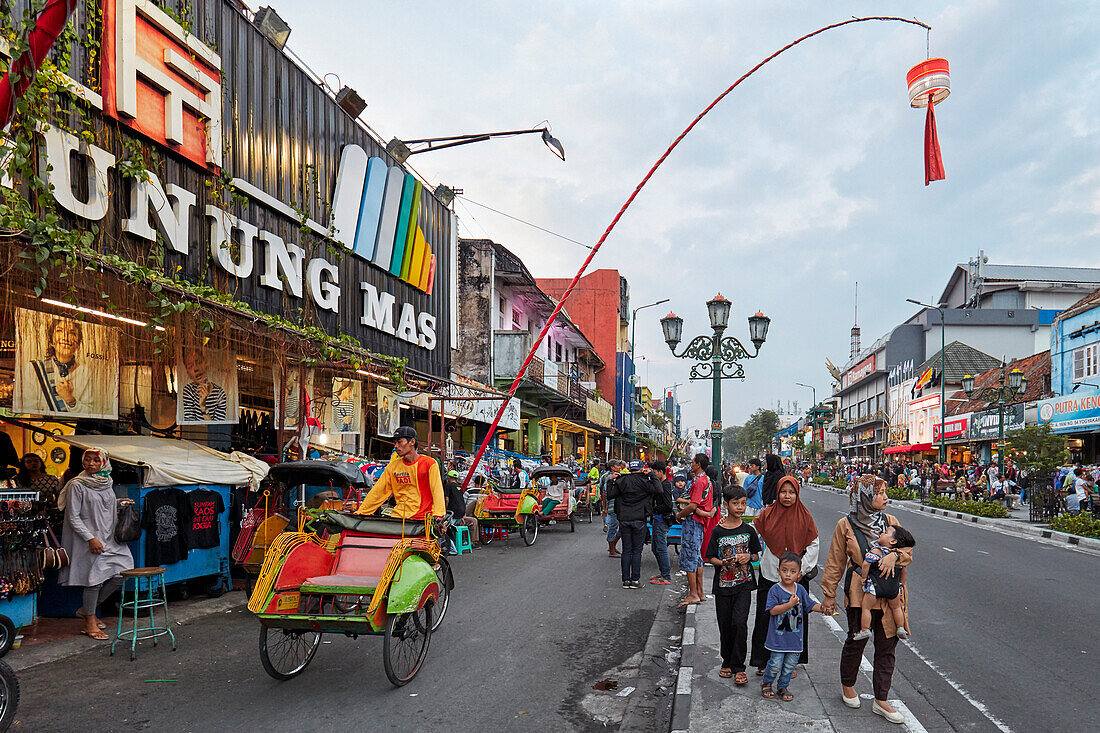 Cycle rickshaw drives in Malioboro Street at dusk. Yogyakarta, Java, Indonesia.