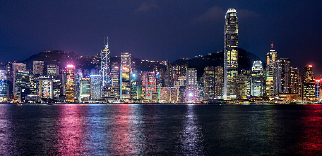  Panoramablick auf nachts beleuchtete Hochhäuser am Wasser. Hongkong, China. 