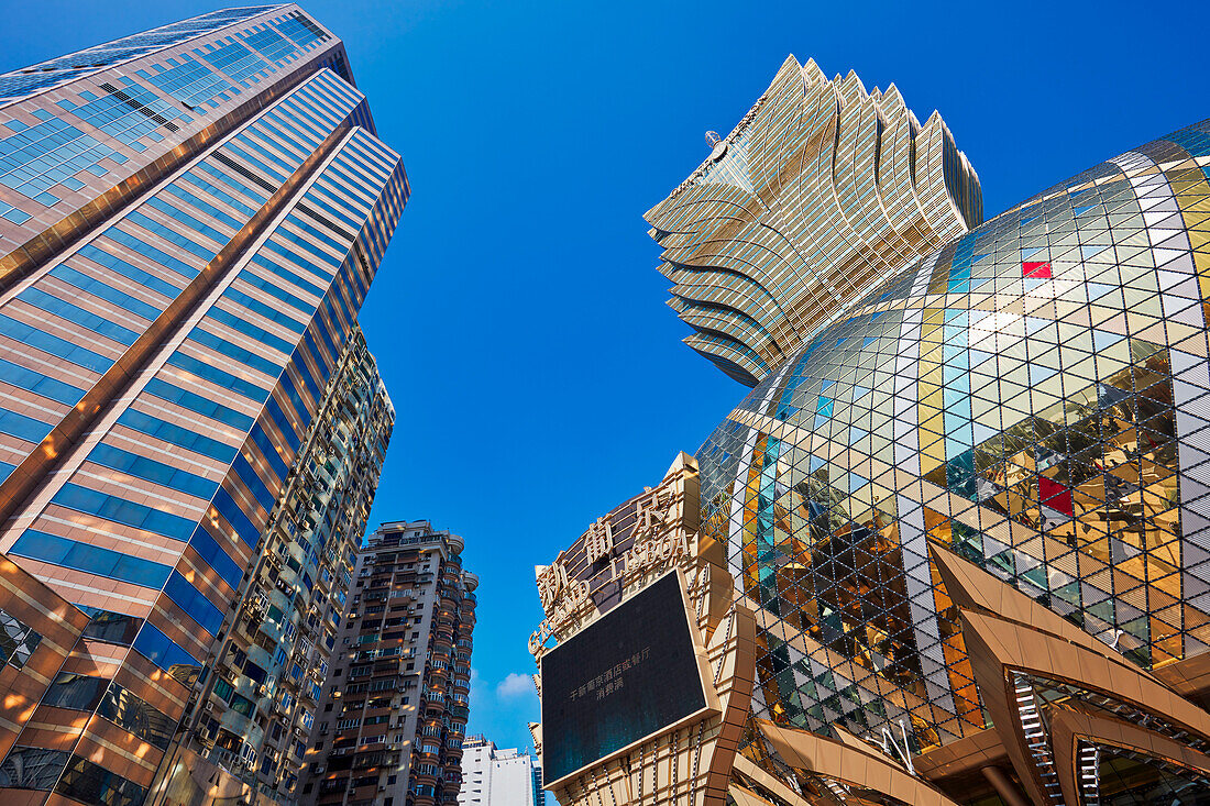 A view from below of the shiny golden dome of the Hotel Grand Lisboa and nearby high-rise buildings. Macau, China.