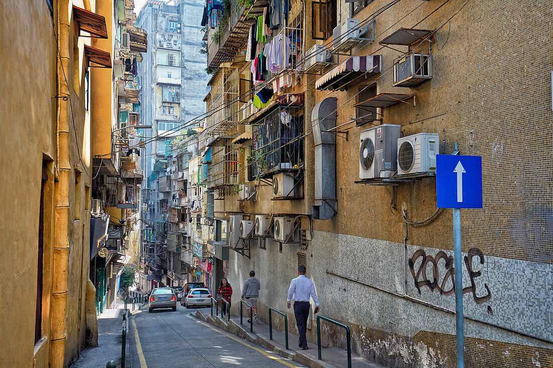 Menschen gehen eine schmale Straße im historischen Zentrum der Stadt Macau, China