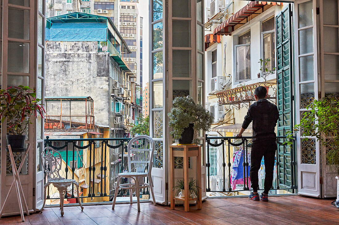 Ein Mann genießt die Aussicht von der Terrasse im obersten Stockwerk des Dom Pedro V Theater. Macau, China.