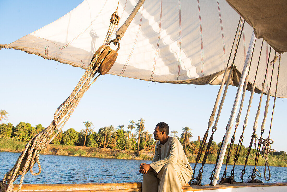 Einheimischer auf Dahabeah Schiff unter Segeln, Passagier-Flussschiff der Lazuli-Flotte, auf dem Nil bei Sonnenuntergang, bei Assuan, Ägypten, Nordostafrika