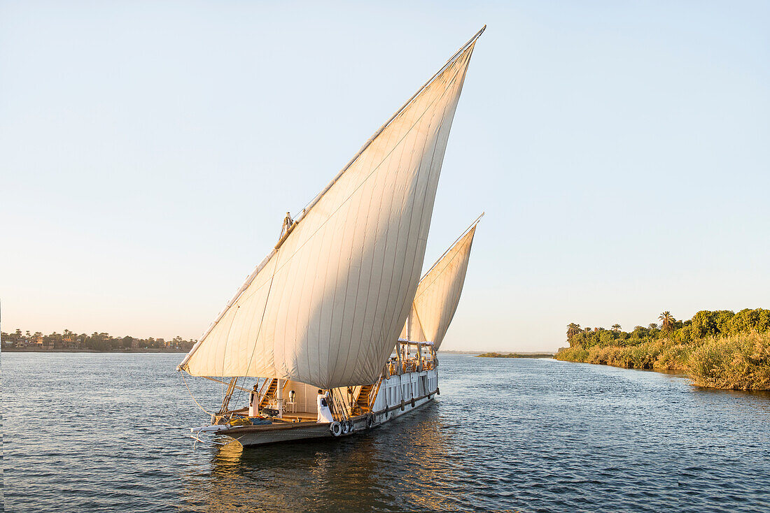 Dahabeah Schiff unter Segeln, Passagier-Flussschiff der Lazuli-Flotte, auf dem Nil bei Sonnenuntergang, bei Assuan, Ägypten, Nordostafrika