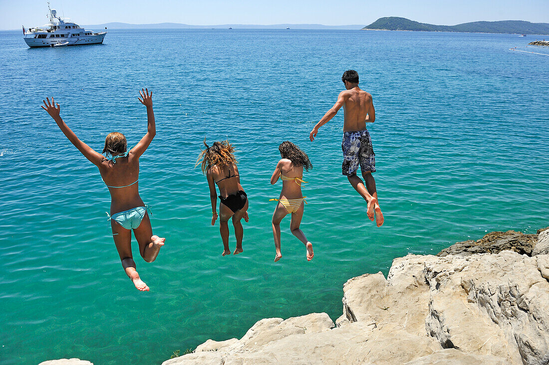 Jugendliche springen von Felsen ins Meer, beim Strand Jezinac am Fuße des Hügels Marjane, Split, Dalmatien, Kroatien, Südosteuropa