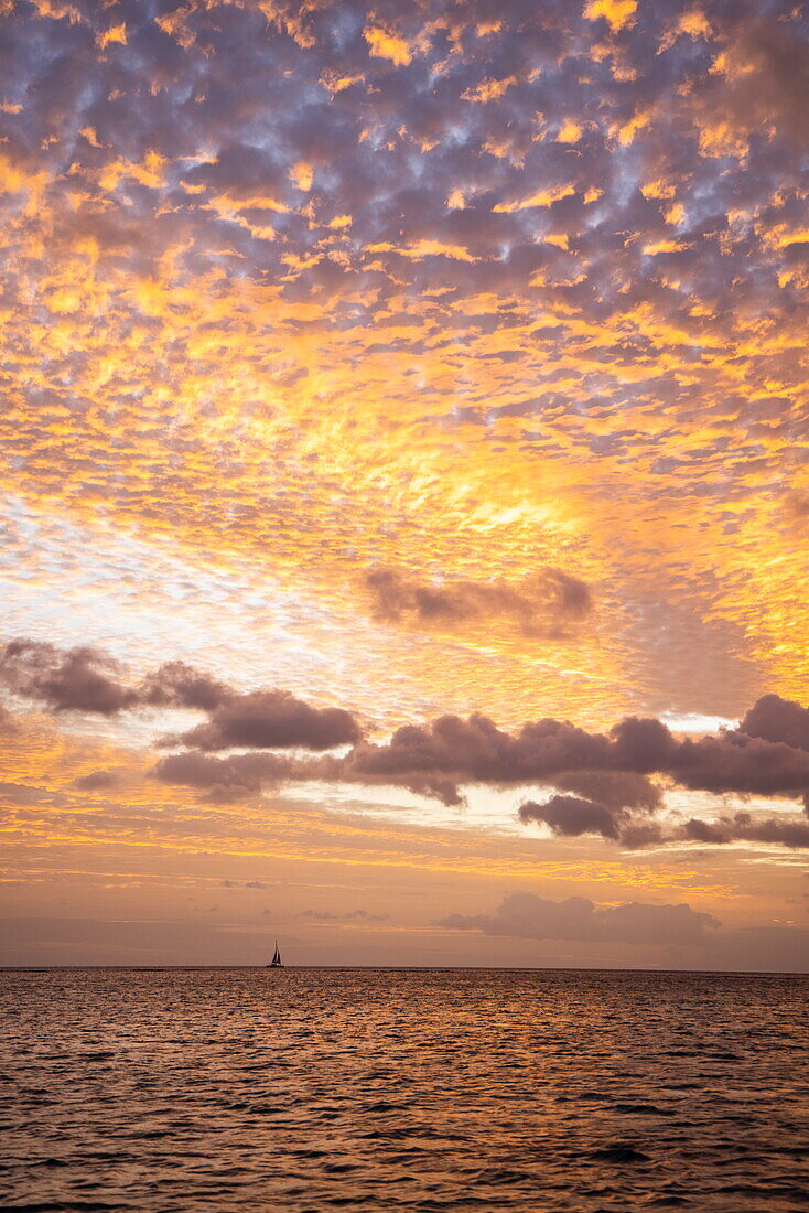  Silhouette of a sailboat and dramatic clouds at sunset, Trou aux Biches, Pamplemousses, Mauritius, Indian Ocean 