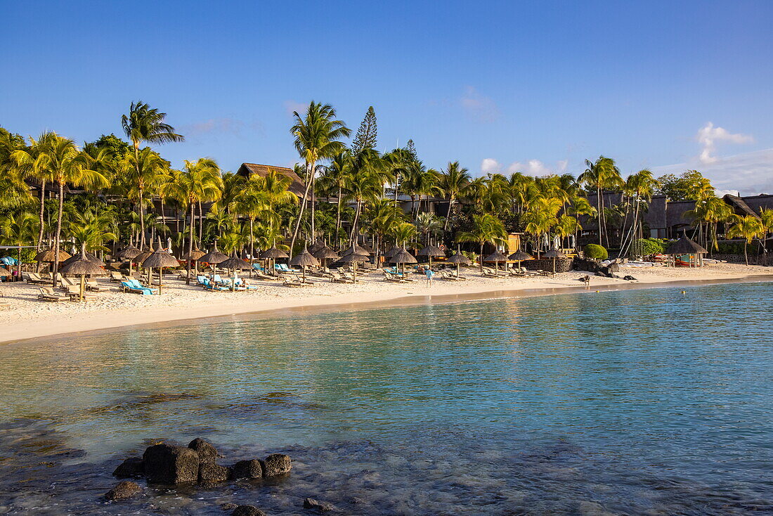 Liegestühle und Strohschirme am Strand mit Kokospalmen im Royal Palms Beachcomber Resorts, Grand Baie, Rivière du Rempart, Insel Mauritius, Indischer Ozean