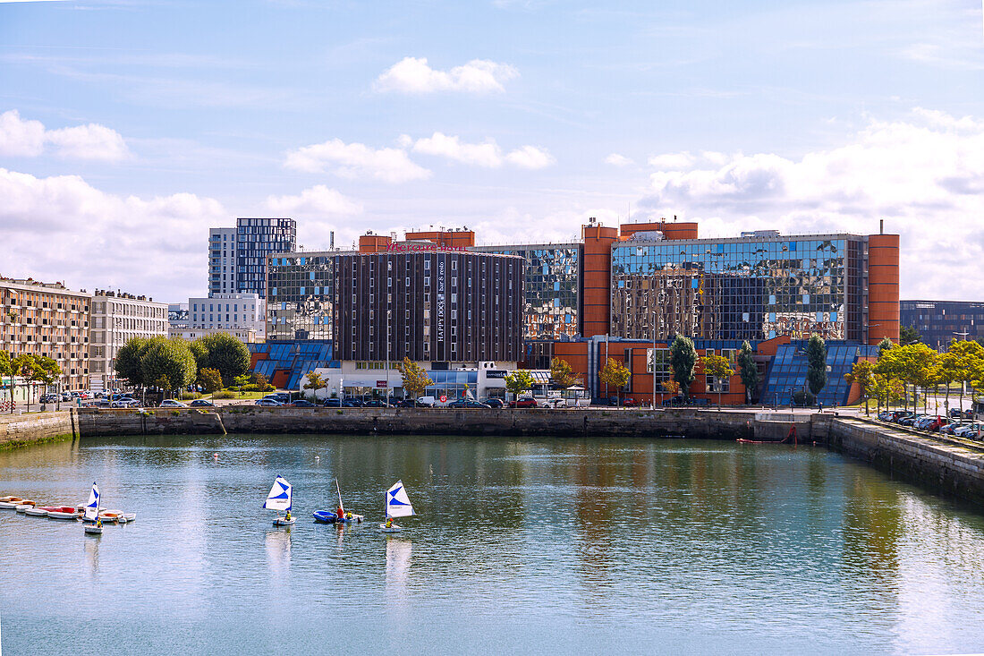  Bassin du Commerce with training boats of the sailing school and view of the Quai d&#39;Angoulême (Angouleme) with Hotel Mercure Le Havre Centre and building of the radio station NRJ in Le Havre on the Alabaster Coast (Côte d&#39;Albatre, Cote d&#39;Albatre) in the Seine-Maritime department in the Normandy region of France 